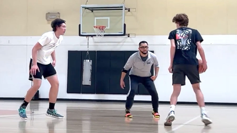 An action shot of basketball trainer, Coach Mondo, training 2 high school boys in Littleton, Colorado